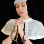 Nun in habit with rosary and cross.