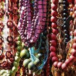 Colorful necklaces hanging on brick wall.