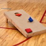 Cornhole board and bags on wooden floor.