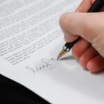 Person signing a contract with a pen.