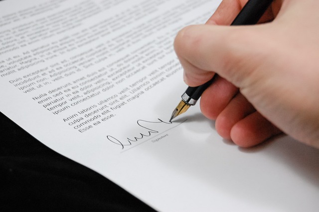 Person signing a contract with a pen.