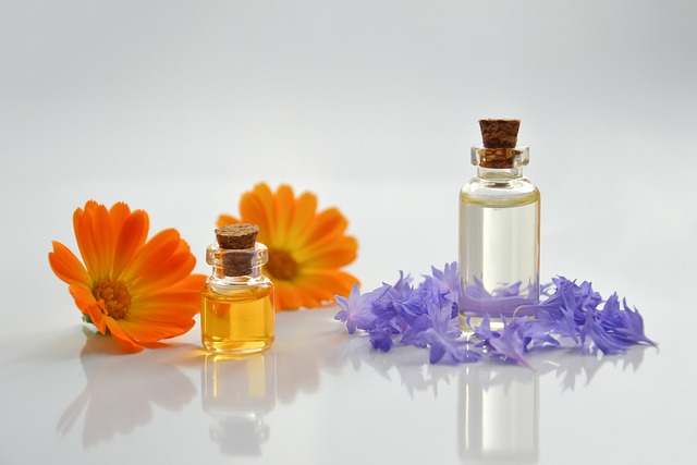 Essential oils and beautiful flowers arranged on a white surface.