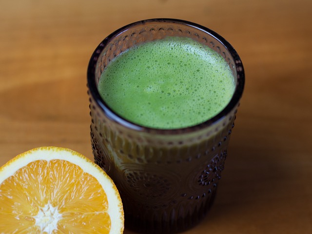 Healthy green drink and a ripe orange placed together.