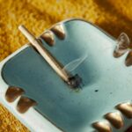 A small blue ashtray with a cigarette resting in it.