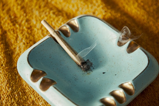 A small blue ashtray with a cigarette resting in it.