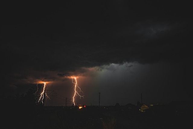 Lightning strikes over dark sky with distant light.