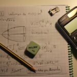 Calculator, pencil, and notebook on table.