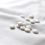 White pills scattered on a white bedspread, creating a stark contrast in color and texture.