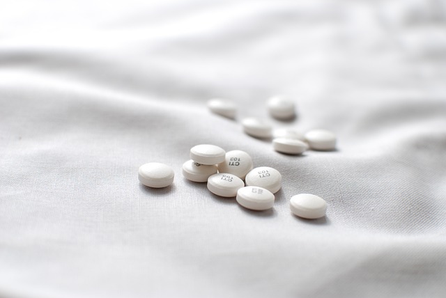 White pills scattered on a white bedspread, creating a stark contrast in color and texture.