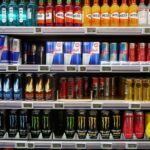 Assorted drinks displayed on a store shelf, such as soft drinks, energy drinks, and flavored water.