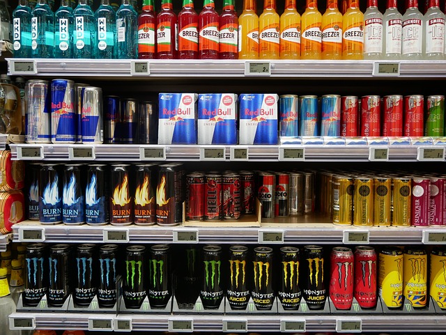 Assorted drinks displayed on a store shelf, such as soft drinks, energy drinks, and flavored water.