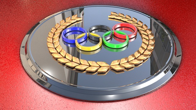 Olympic rings on metal plate against red background.