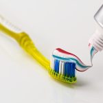 A toothbrush with toothpaste on it, ready for brushing teeth.