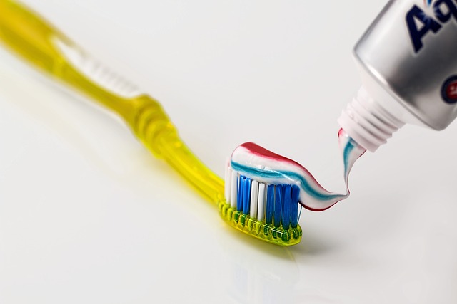 A toothbrush with toothpaste on it, ready for brushing teeth.