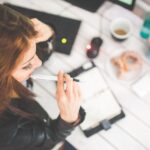 Woman writing on paper at desk.