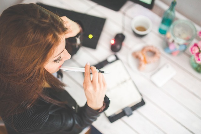 Woman writing on paper at desk.